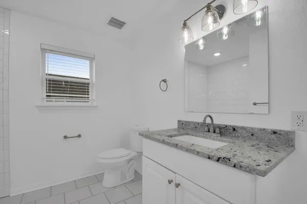 a bathroom with a granite countertop sink a toilet and mirror