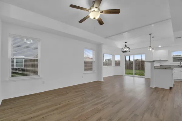 a view of an empty room with window and wooden floor