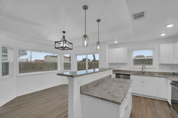 a kitchen with stainless steel appliances granite countertop a sink a stove and a wooden floors