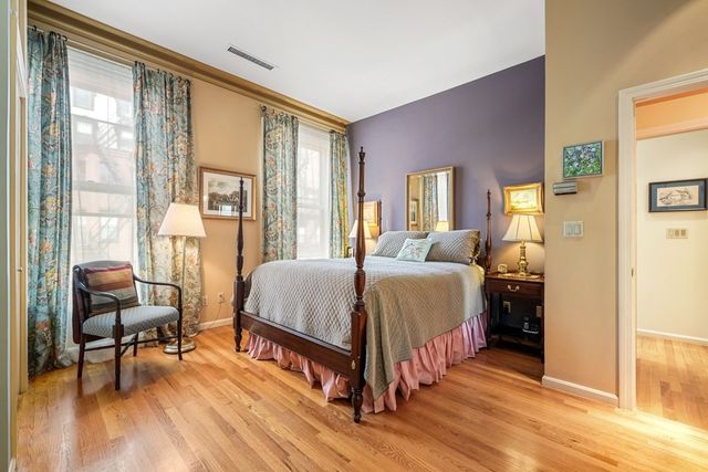 a spacious bedroom with a bed a table and chair with wooden floor