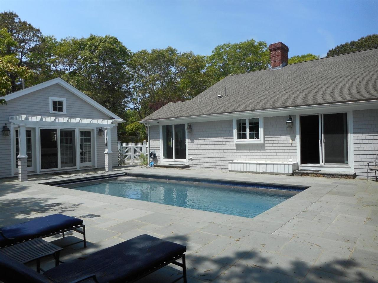 a front view of a house with swimming pool and furniture