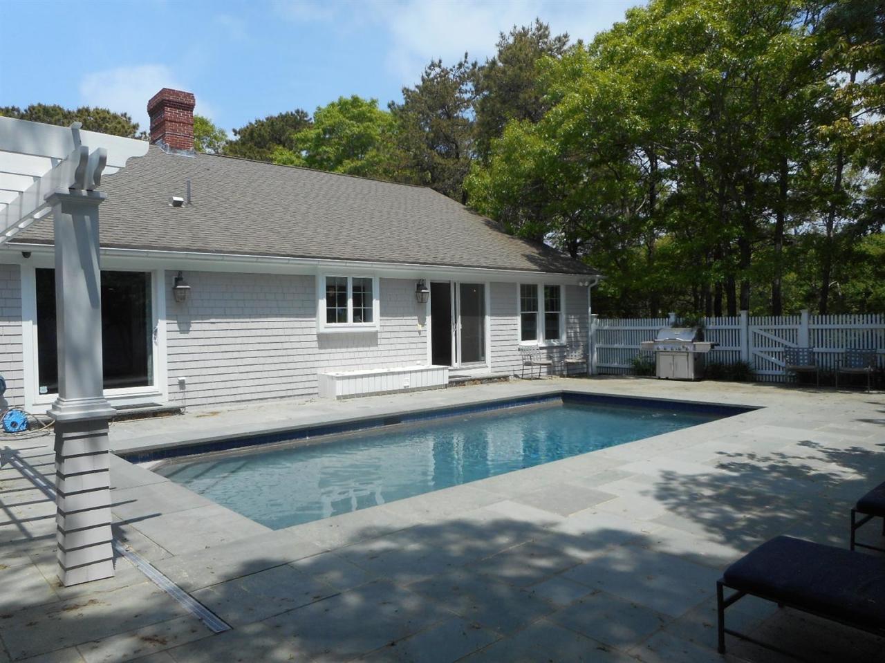 84 Troon Way Mashpee, MA 02649 - Photo 31 of 31 a view of a house with pool lawn chairs under an umbrella