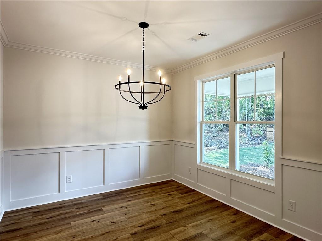10 Lee Road Salem, AL 36874 - Photo 4 of 25 Wood-finish flooring, wainscoting with picture frame molding, crown molding, double-hung windows, and a black metal chandelier