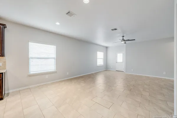 an empty room with windows and chandelier fan