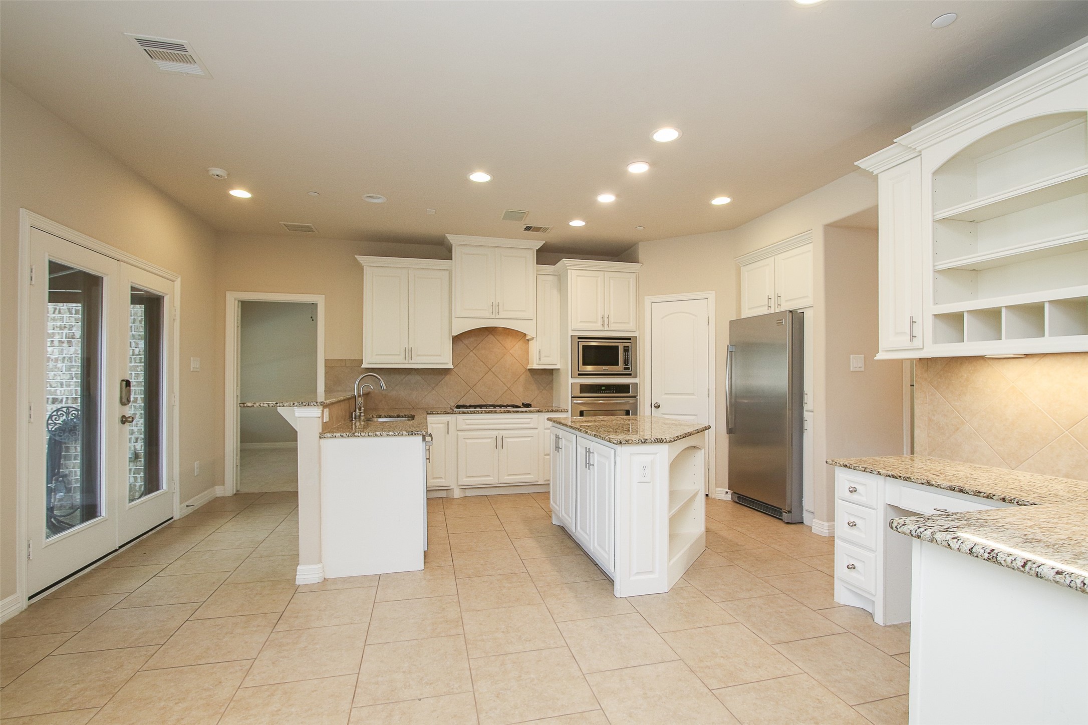 11722 Spriggs Way Houston, TX 77024 - Photo 16 of 49 Spacious open kitchen with plenty of cabinets, stainless appliances, work desk to the right and double patio doors leading to the backyard pool area.