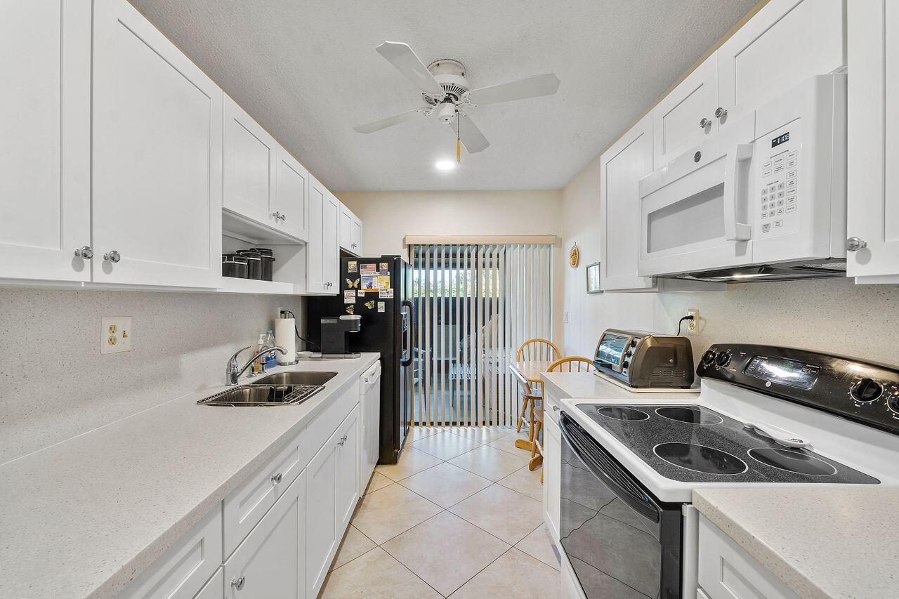 5130 Nesting Way, Unit D Delray Beach, FL 33484 - Photo 11 of 41 a kitchen that has a sink a stove and cabinets