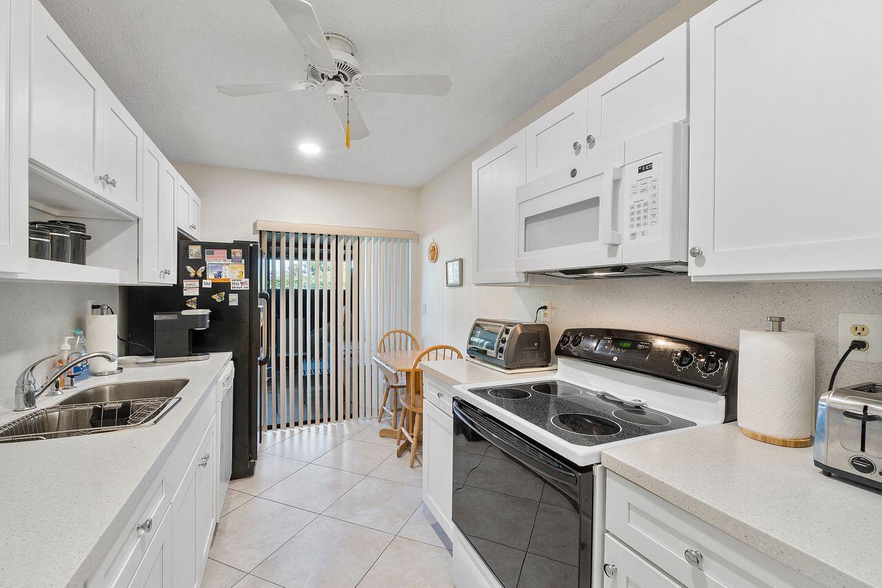 5130 Nesting Way, Unit D Delray Beach, FL 33484 - Photo 12 of 41 a kitchen with stainless steel appliances granite countertop a sink stove and refrigerator