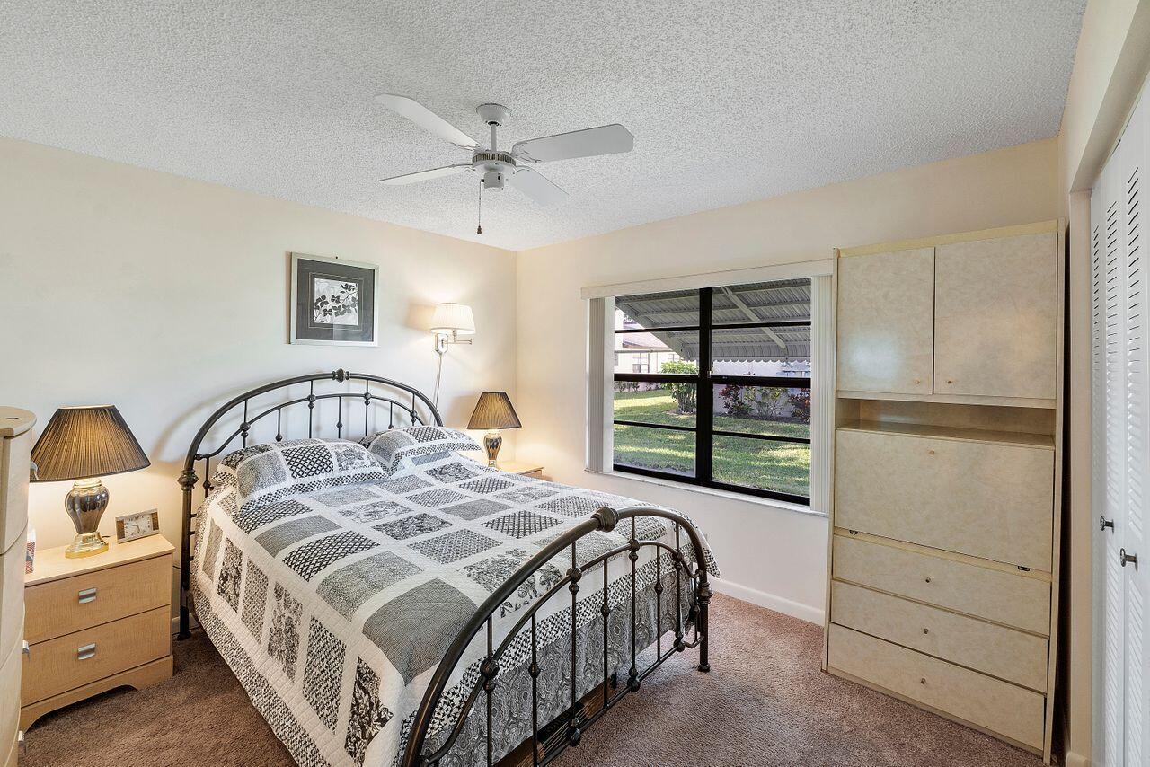 5130 Nesting Way, Unit D Delray Beach, FL 33484 - Photo 17 of 41 a bedroom with a bed a lamp and window