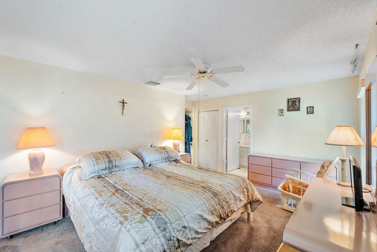 5130 Nesting Way, Unit D Delray Beach, FL 33484 - Photo 23 of 41 a bedroom with a bed and a lamp on table