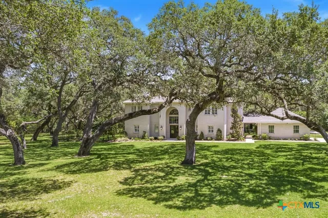 a white house with a big yard and large trees
