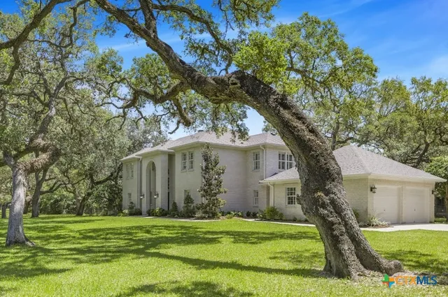 a white house in a yard with large trees