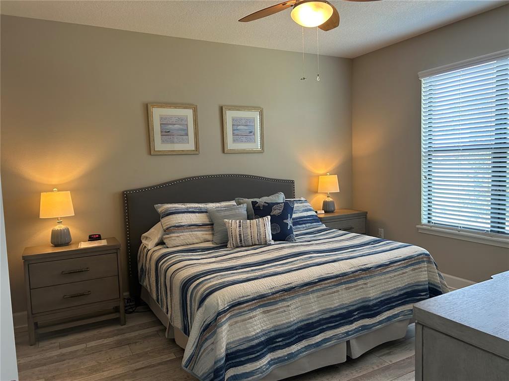 13711 Messina Loop, Unit 203 Lakewood Ranch, FL 34211 - Photo 14 of 27 a bedroom with bed and lamps with wooden floor