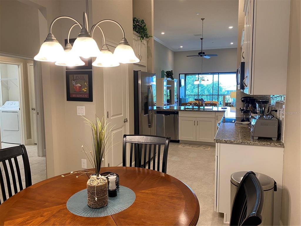 13711 Messina Loop, Unit 203 Lakewood Ranch, FL 34211 - Photo 5 of 27 a kitchen with stainless steel appliances wooden floor dining table and chairs