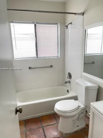 a bathroom with a toilet a bath tub and a window