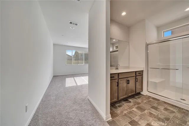 a view of a hallway to an empty room with cabinet and a window