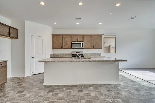a large kitchen with kitchen island a sink a stove a refrigerator and white cabinets