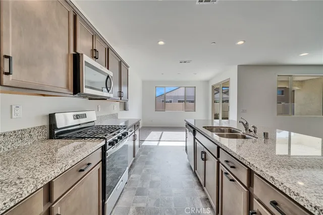 a kitchen with stainless steel appliances granite countertop a stove a sink and a microwave