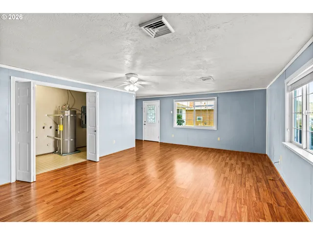 an empty room with wooden floor and windows