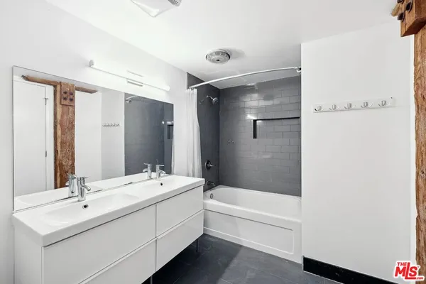 a bathroom with a double vanity sink mirror and bathtub