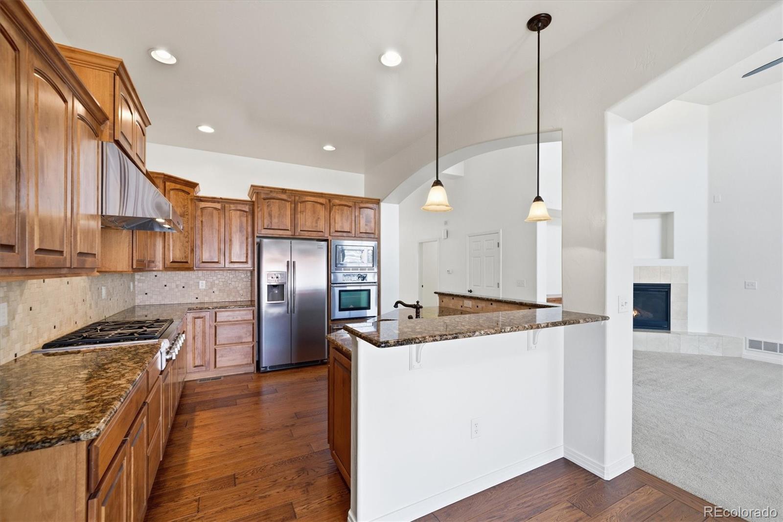 477 Rifle Way Broomfield, CO 80020 - Photo 11 of 45 a kitchen with stainless steel appliances granite countertop a refrigerator a oven and white cabinets with wooden floors