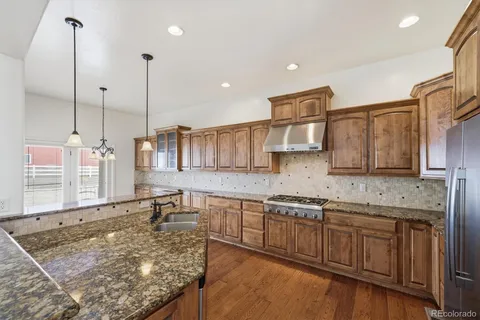 a kitchen with stainless steel appliances granite countertop a sink a stove and a wooden cabinets
