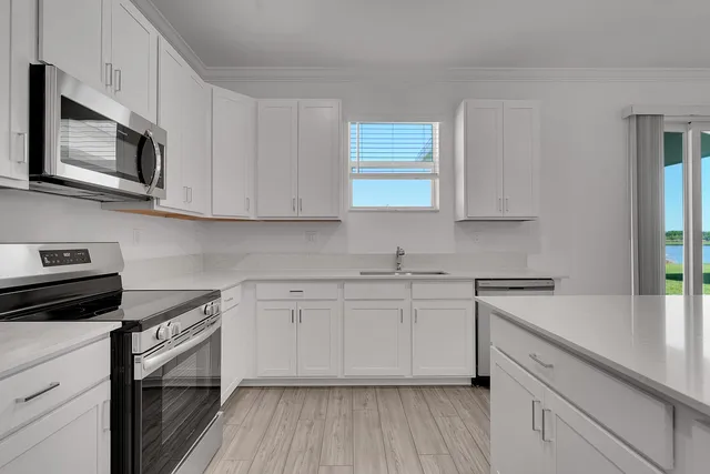 a kitchen with stainless steel appliances granite countertop white cabinets granite counter tops and a wooden floors