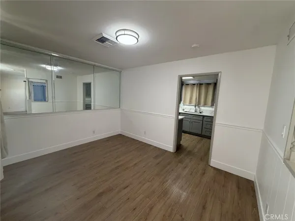 an empty room with wooden floor and a sink