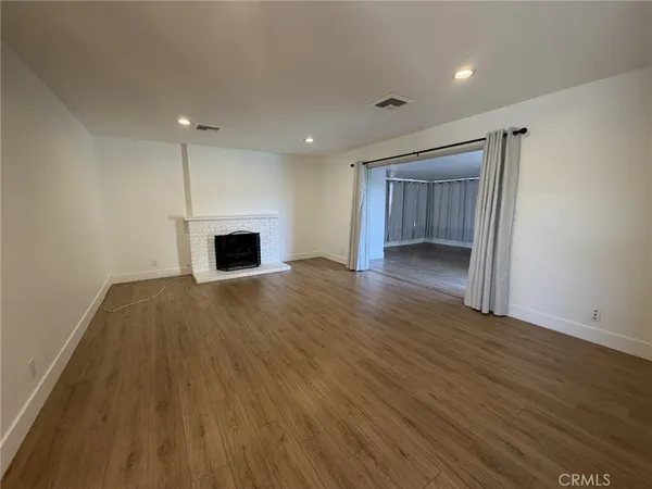 an empty room with wooden floor fireplace and windows