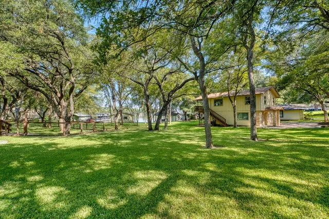 a view of a house with a yard fire pit and a large tree