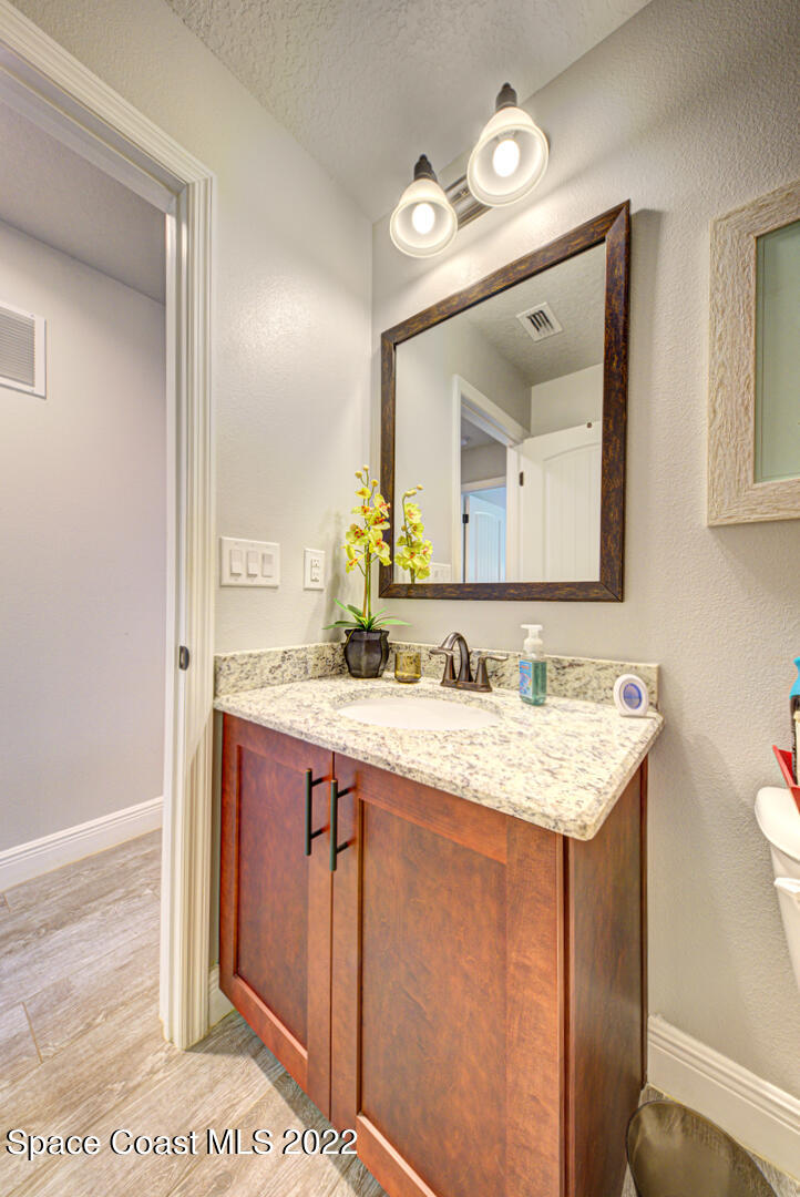 3945 Post Road Melbourne, FL 32934 - Photo 12 of 24 a bathroom with a granite countertop sink a large mirror and a toilet
