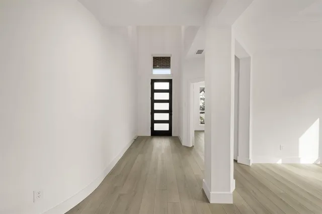 a view of an empty room with wooden floor and closet