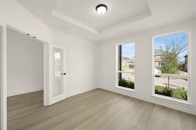 an empty room with wooden floor and windows