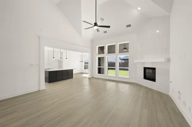 a view of an empty room with wooden floor and a fireplace