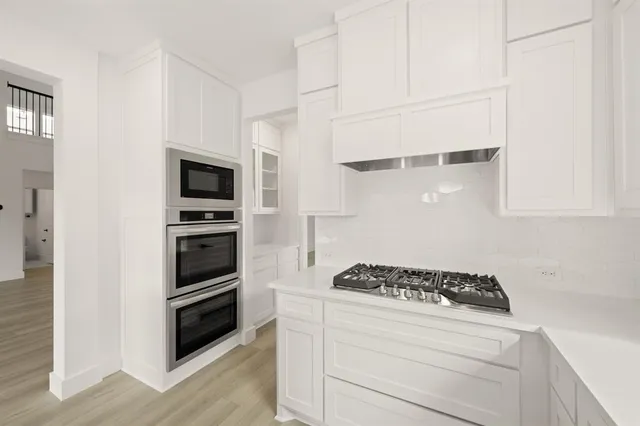 a kitchen with white cabinets and appliances