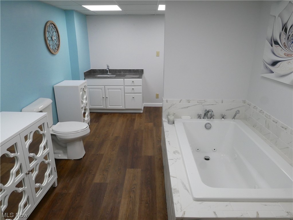 62818 Chestnut Road Bellaire, OH 43906 - Photo 15 of 18 Bathroom featuring hardwood / wood-style floors, tiled tub, toilet, and vanity