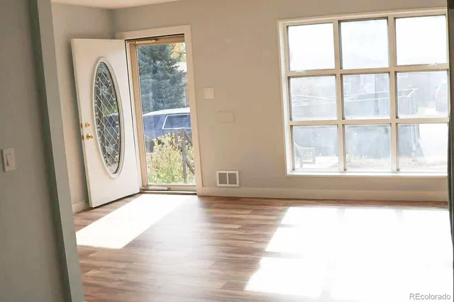 a view of an empty room with a window and wooden floor