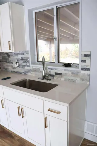 a view with granite countertop a sink window and cabinets