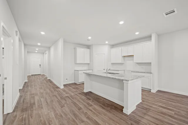 a kitchen with stainless steel appliances granite countertop a white cabinets and wooden floors