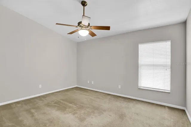an empty room with windows and fan