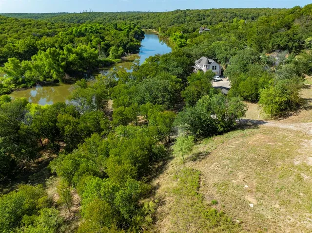 an aerial view of green landscape with trees houses and lake view