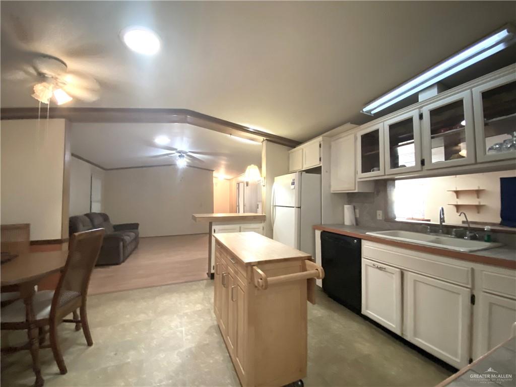 219 Bundle Wagon Drive Mission, TX 78574 - Photo 14 of 30 Kitchen featuring black dishwasher, a center island, glass insert cabinets, freestanding refrigerator, and white cabinetry