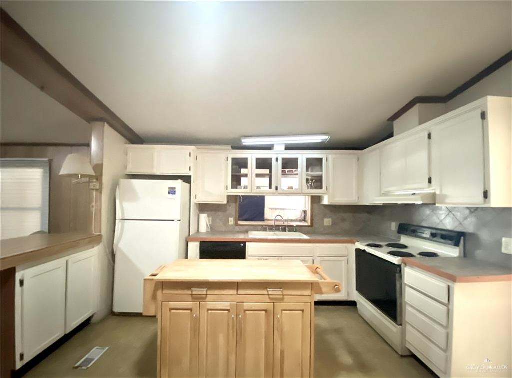 219 Bundle Wagon Drive Mission, TX 78574 - Photo 6 of 30 Kitchen featuring white appliances, a center island, decorative backsplash, glass insert cabinets, and white cabinetry