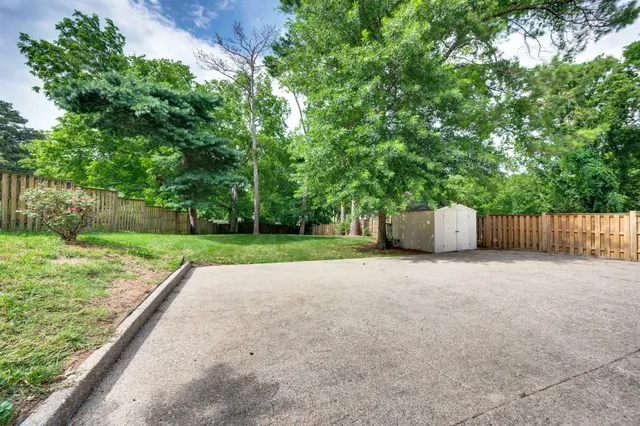 a backyard of a house with large trees and wooden fence