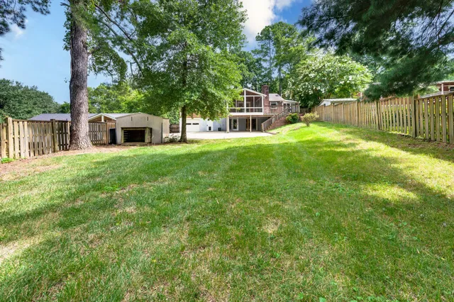 a view of a house with a yard and large tree