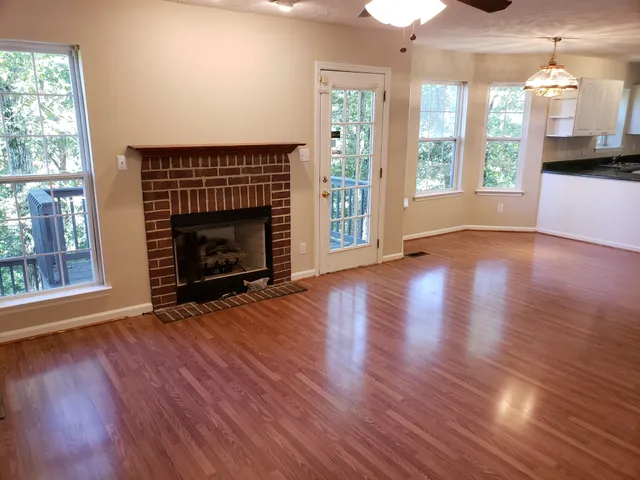 an empty room with wooden floor fireplace cabinet and windows
