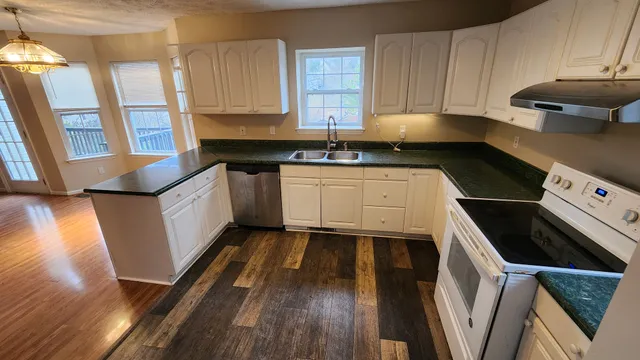 a kitchen with granite countertop a sink a stove and cabinets