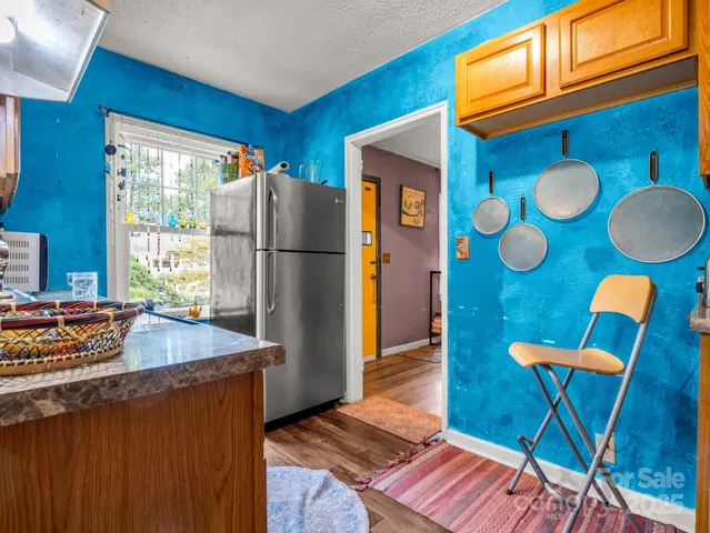 a kitchen with stainless steel appliances granite countertop a refrigerator a sink dishwasher and a dining table with wooden cabinet