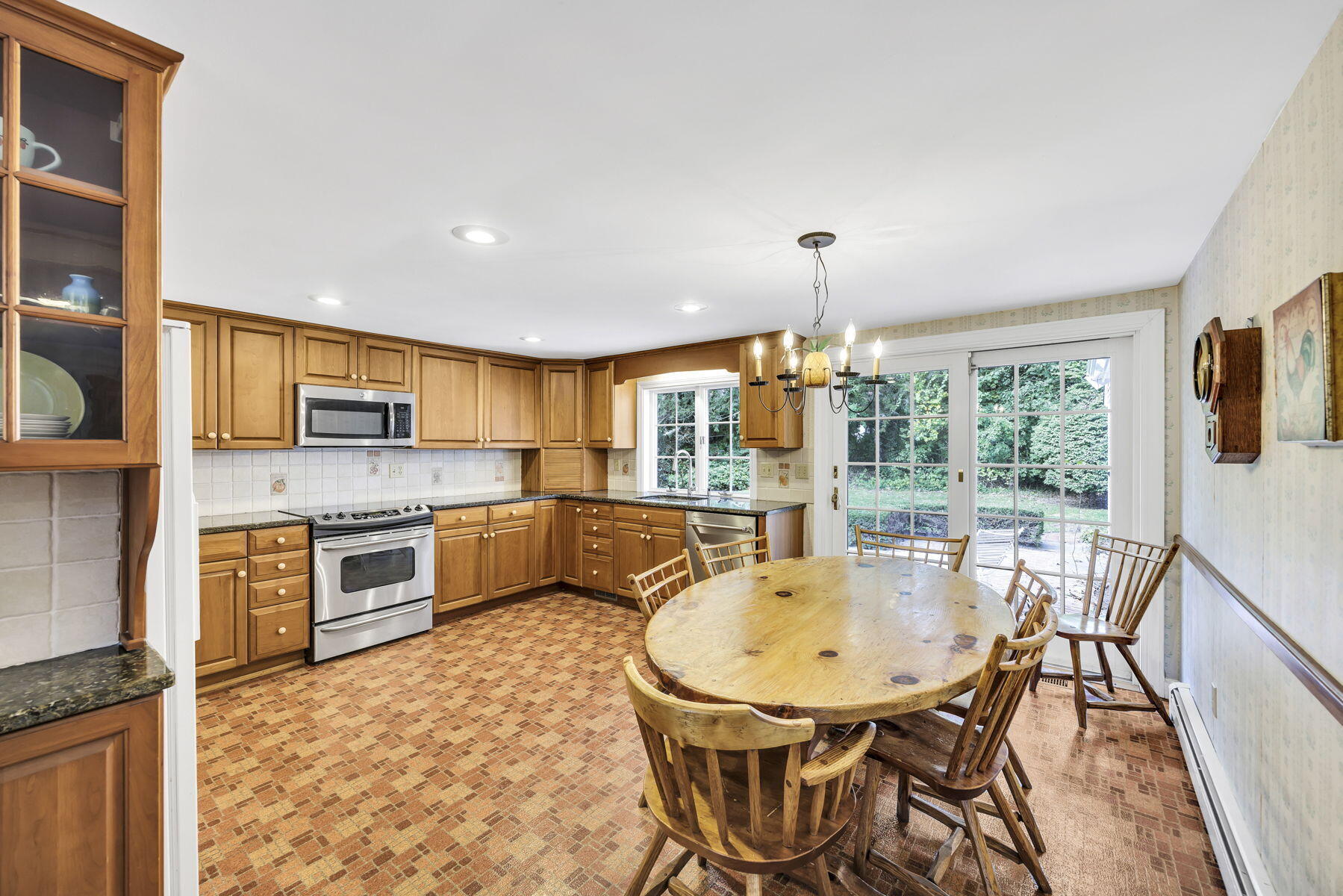 473 Davisville Road East Falmouth, MA 02536 - Photo 8 of 41 a kitchen with stainless steel appliances granite countertop a stove top oven a sink dishwasher a dining table and chairs with wooden floor