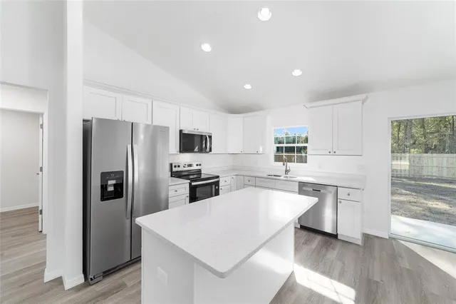 a kitchen with a refrigerator a sink and dishwasher with wooden floor