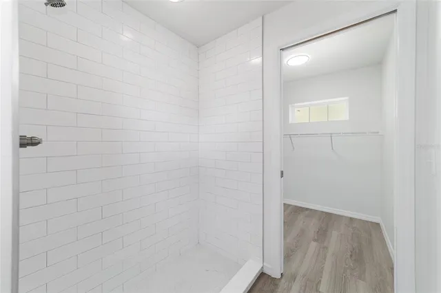 an empty room with wooden floor closet and windows
